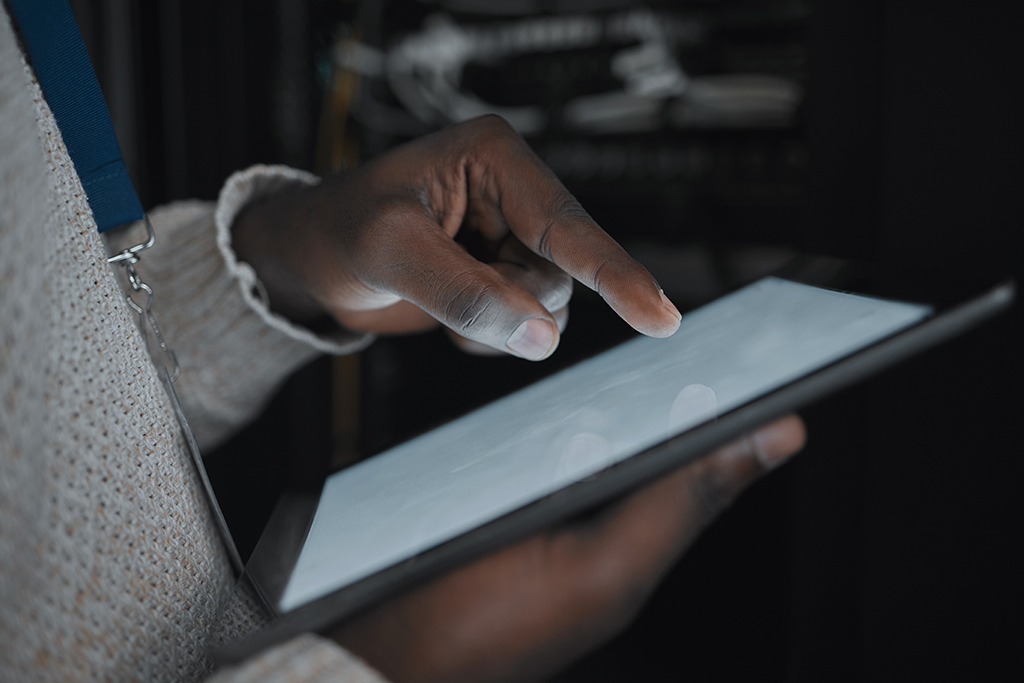 A closeup of a person's hands tapping the screen of a tablet. 