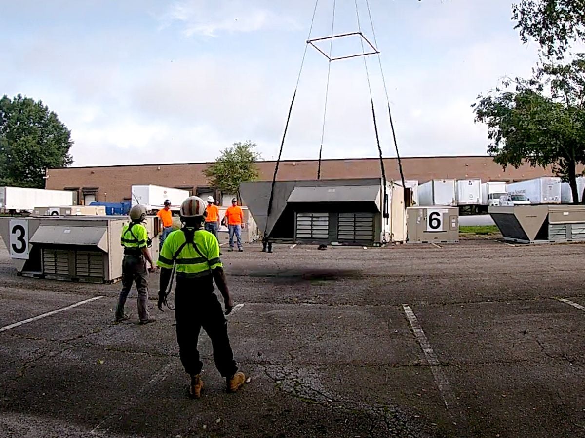 Crew guiding a helicopter lift during a rooftop HVAC replacement
